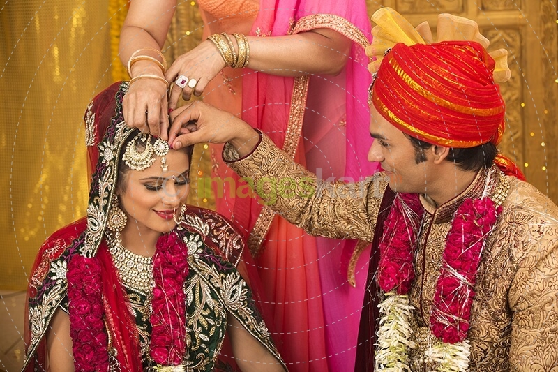 groom applying sindoor to wife