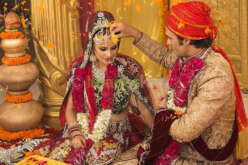 groom applying sindoor to wife