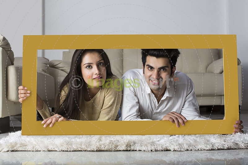 young couple posing with wooden frame at home