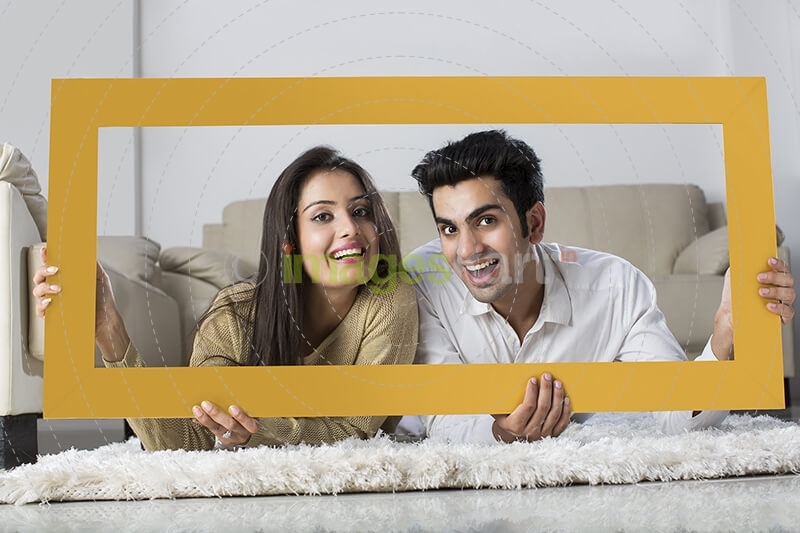 young couple posing with wooden frame at home
