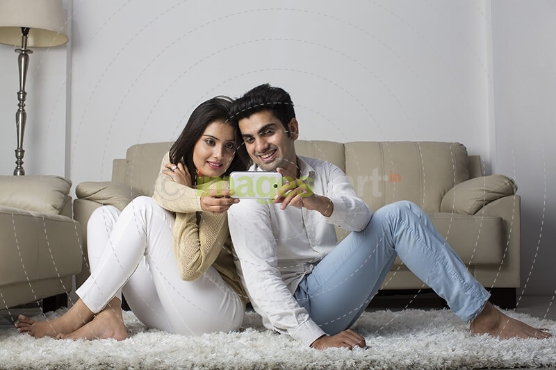 couple clicking picture with mobile phone at home