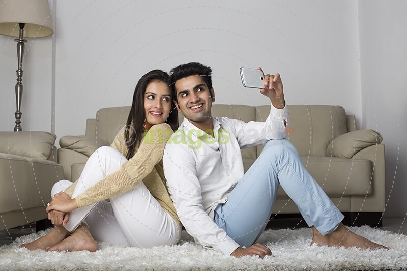 couple clicking picture with mobile phone at home