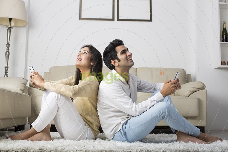 couple at home chatting on mobile phone