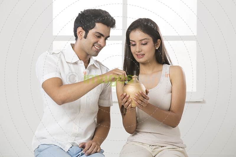 newly wed couple at new home with piggy bank