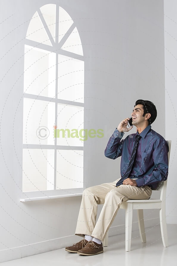 man sitting on chair talking on mobile phone