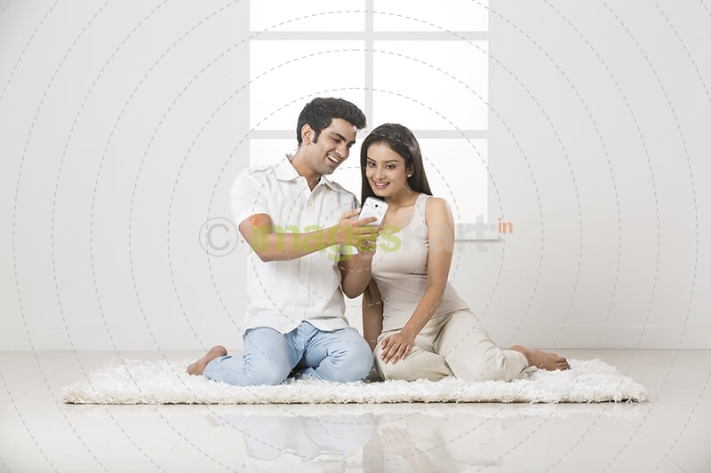 couple clicking picture with mobile phone at home