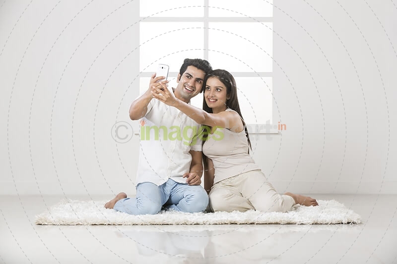 couple clicking picture with mobile phone at home