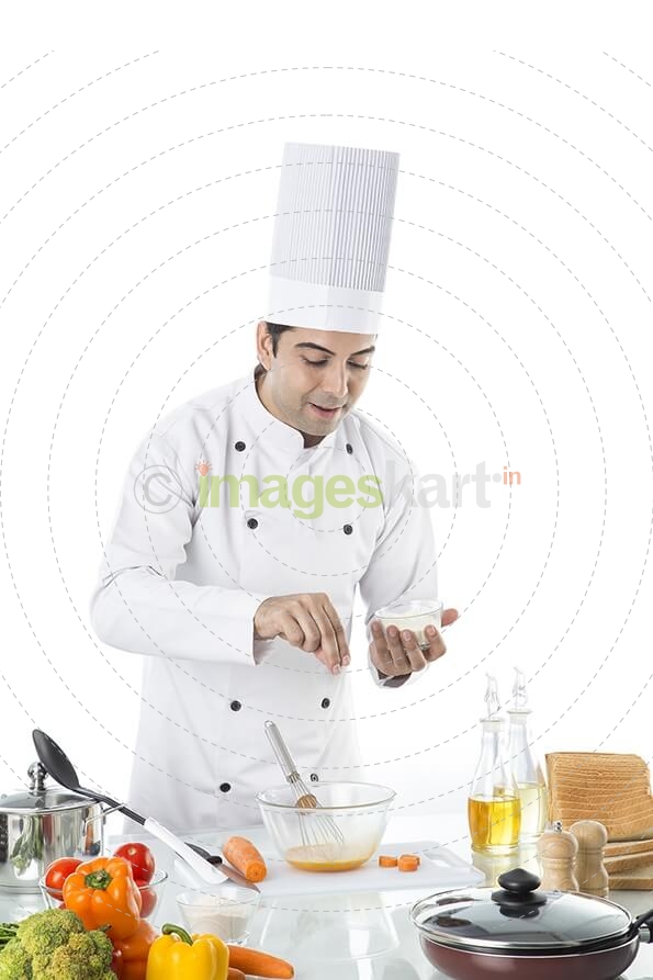 chef adding salt to the bowl 