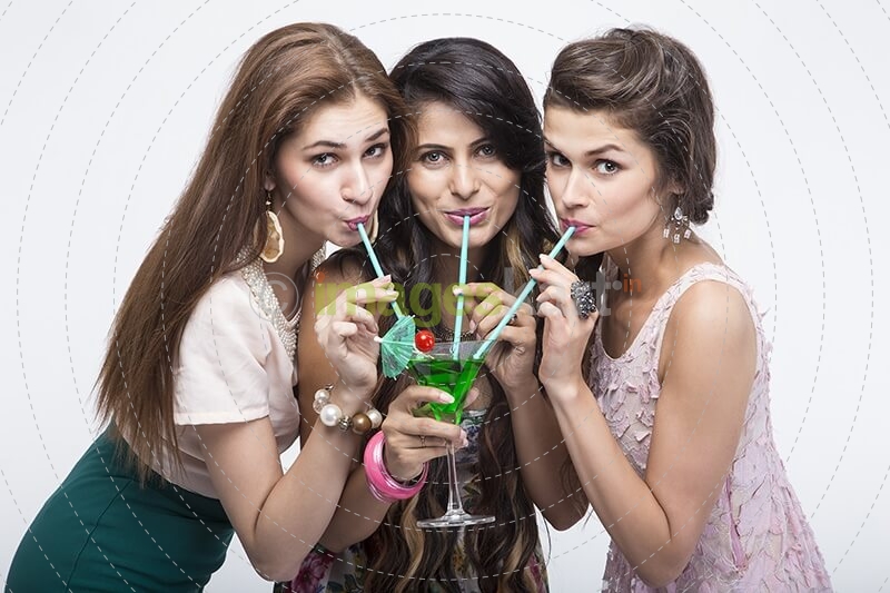 young stylish girls sipping from the mocktail while posing