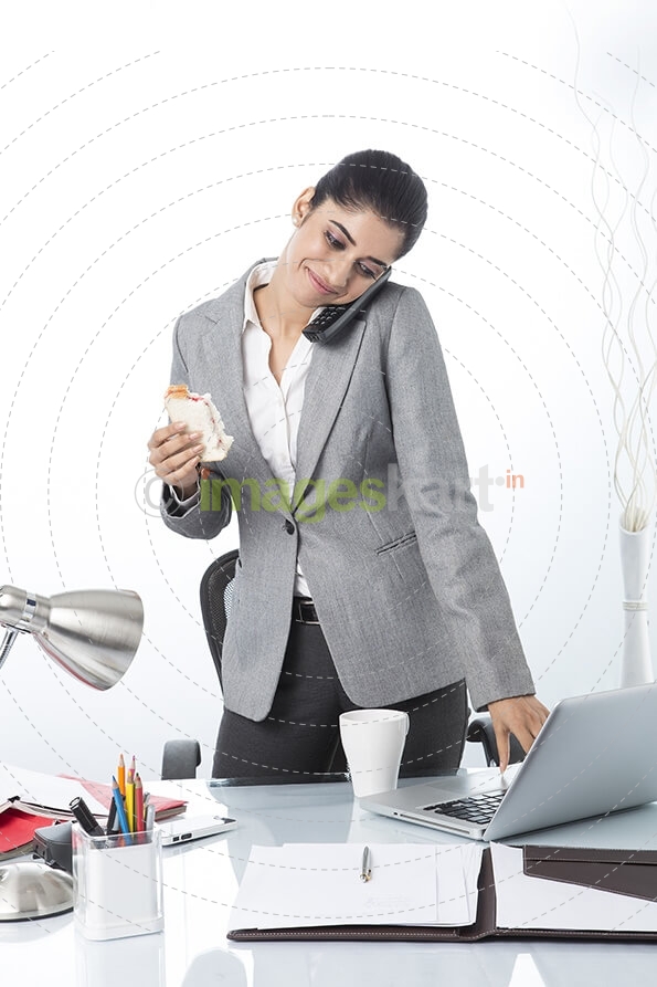 modern woman eating sandwich while working 
