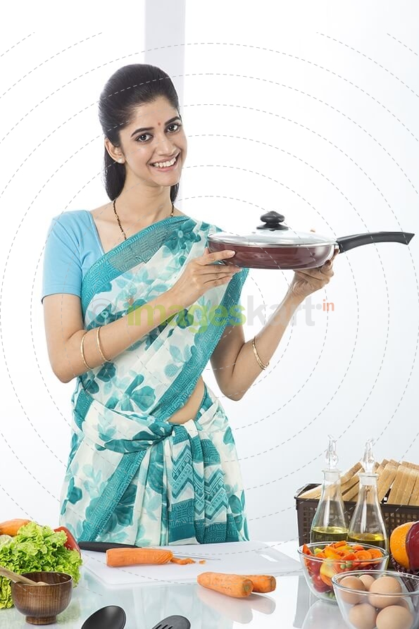 Indian housewife showing pan in kitchen