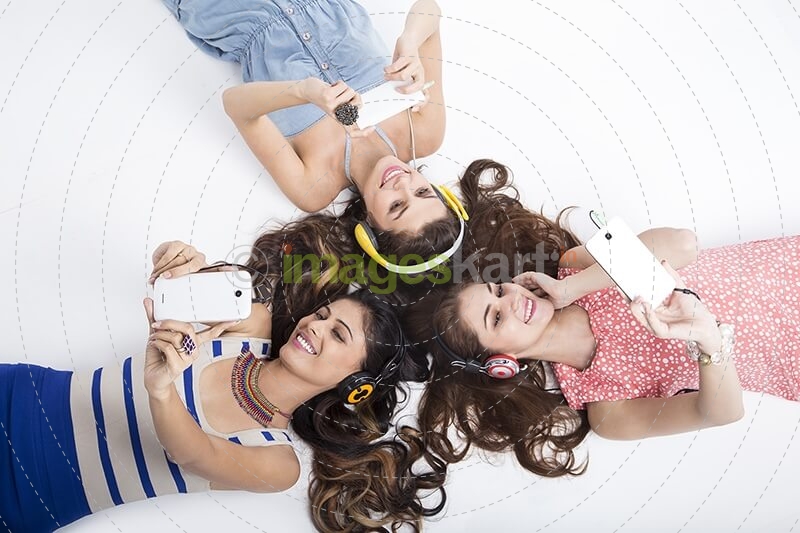 three girls listening to music while lying on back