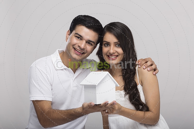 couple posing with toy home