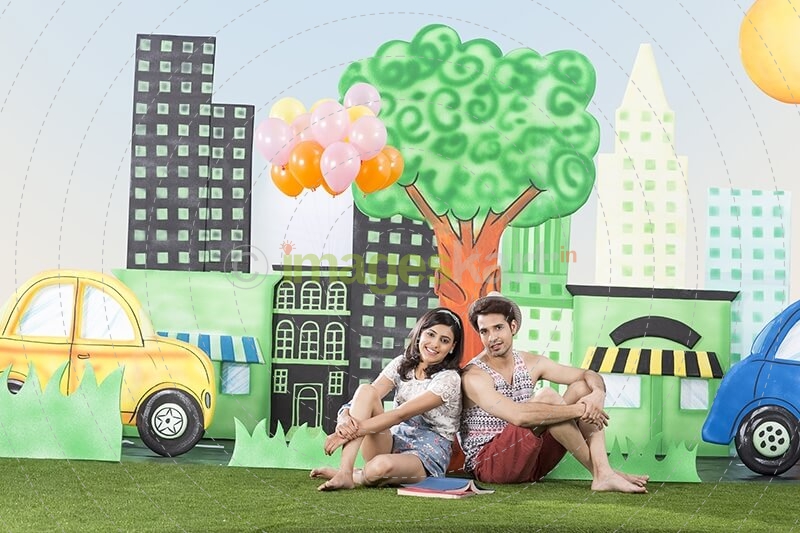 couple sitting back to back in garden holding balloons