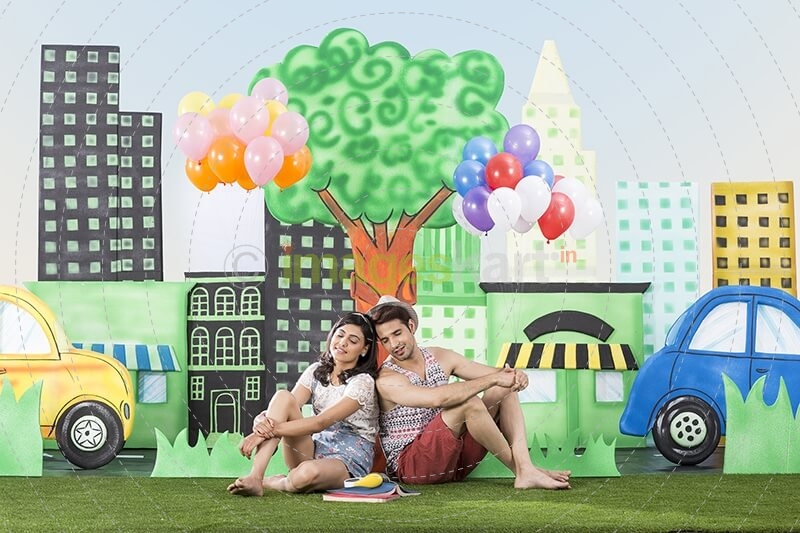 couple sitting back to back in garden holding balloons