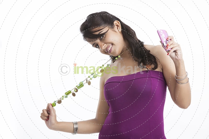 teen girl holding long bead necklace with cell phone