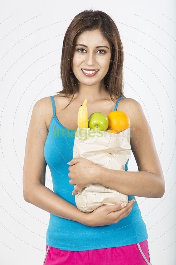 Young girl holding Paper bag full of fruits
