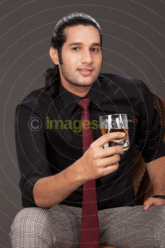 young business guy holding a drink and sitting on a chair