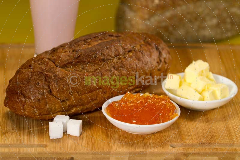bread,butter,jam and sugar cubes on a wooden table