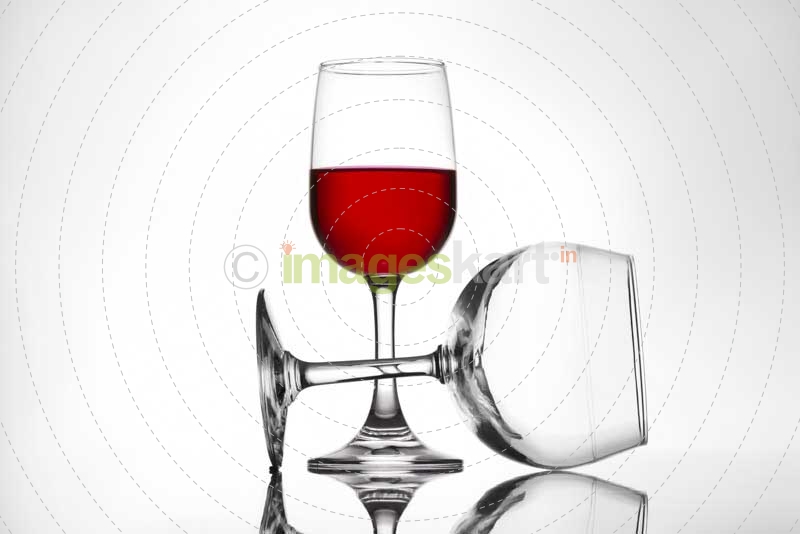 full and empty pair of red wine glasses