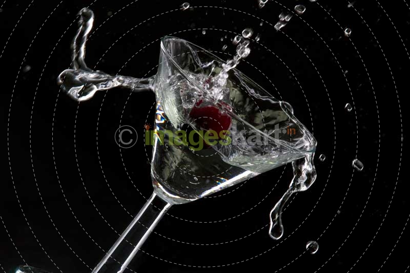 red cherry splashing into cocktail against black background