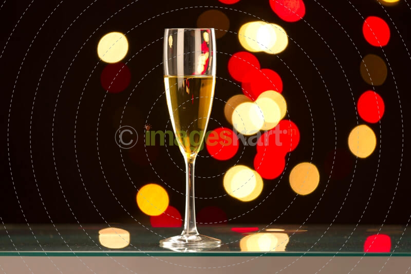 a wine glass on the table with lights in the dark background 