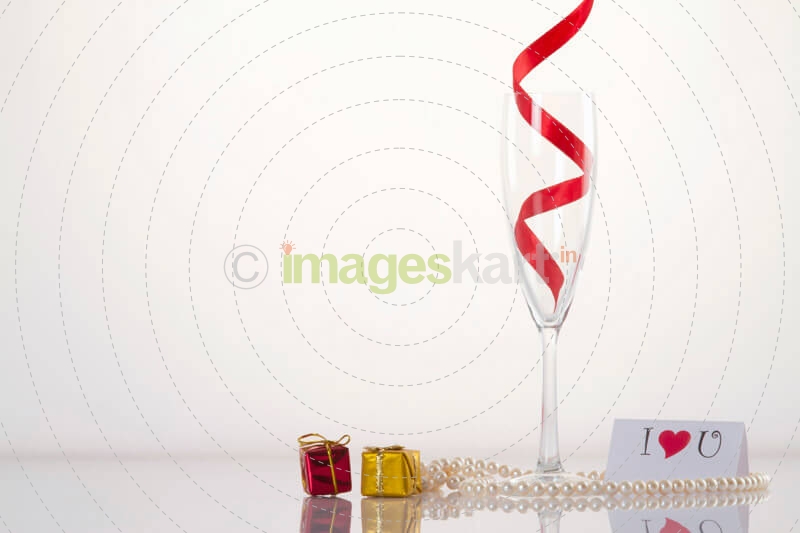 champagne flute with pearls and love note against a white background