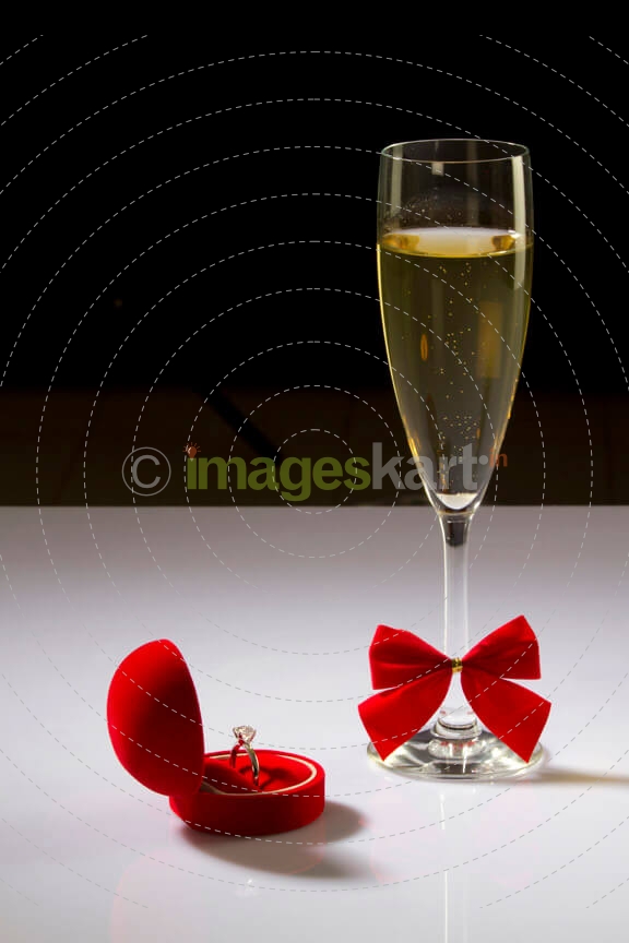 picture of a wine glass and wedding ring on white surface 