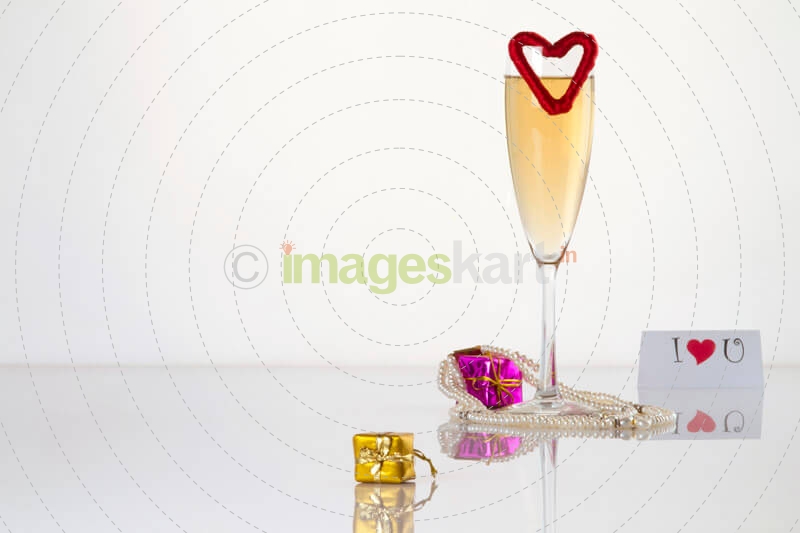 a glass of champagne shot with some gift miniatures and a love note on