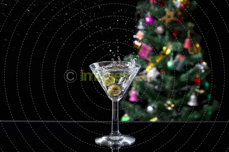 a glass full of martini drink with splash from olives