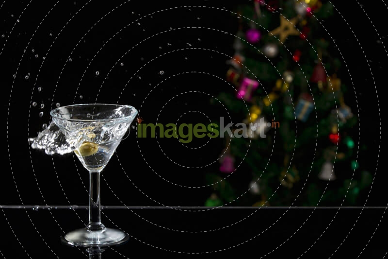 close up shot of martini drink with splash and christmas tree in the b