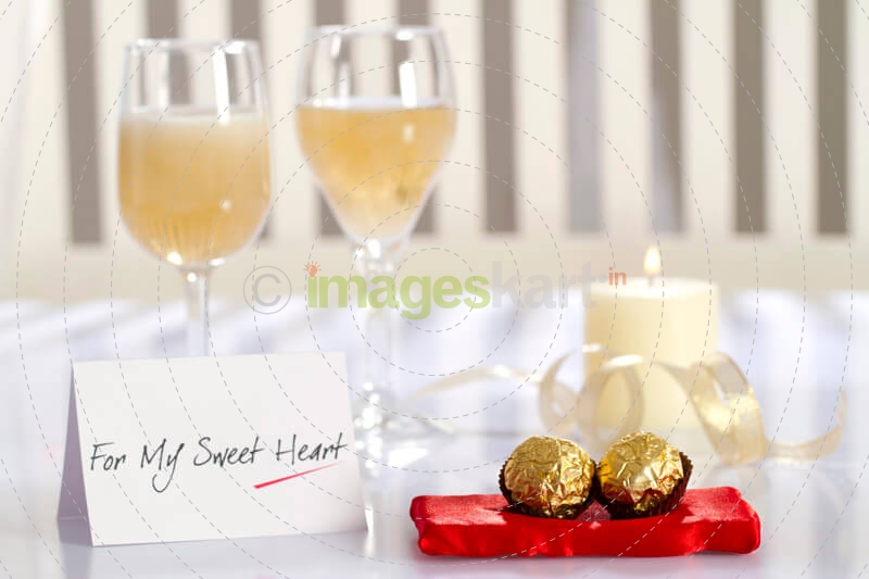 table decorated with chocolates,champagne,love note and scented candle