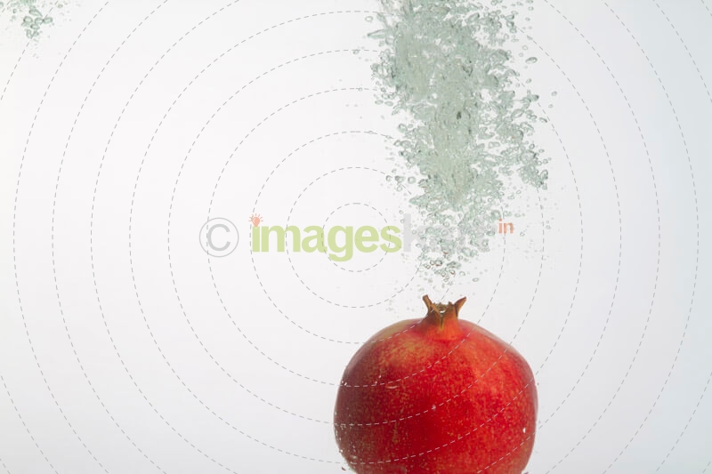 pomegranate dunked into water showing air bubbles