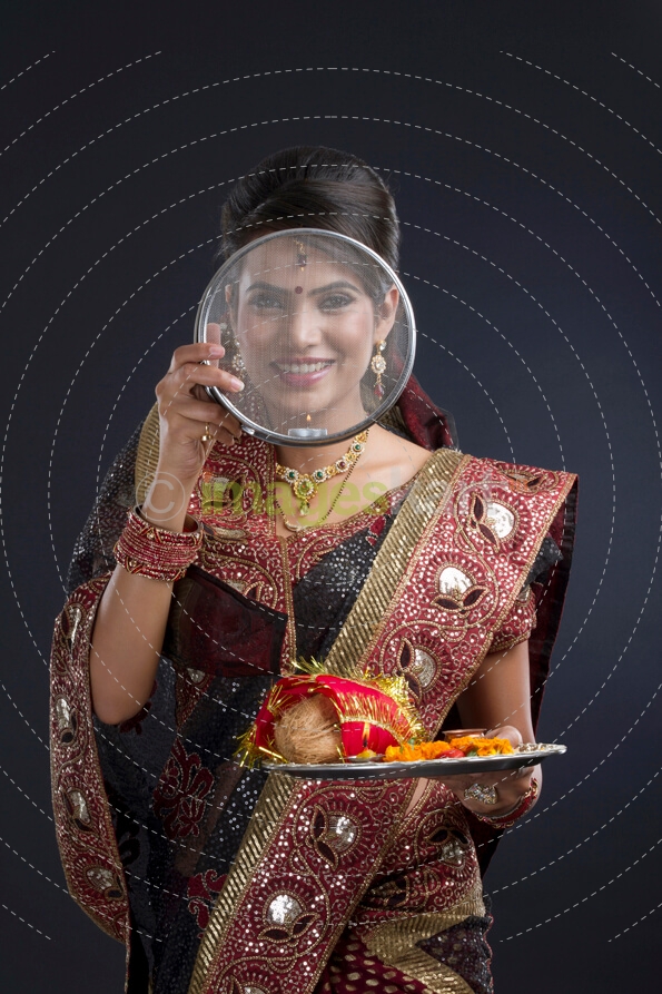 Indian woman looking through the strainer on karva chauth