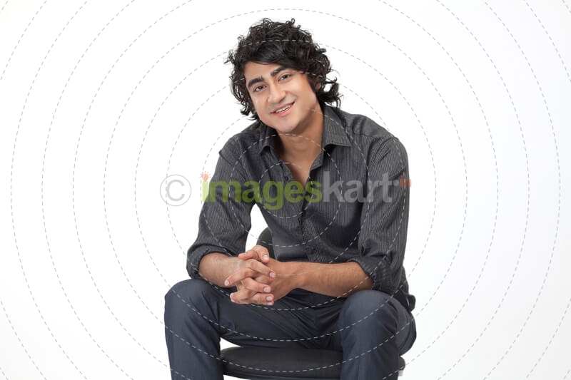a guy in formals sitting on a chair 