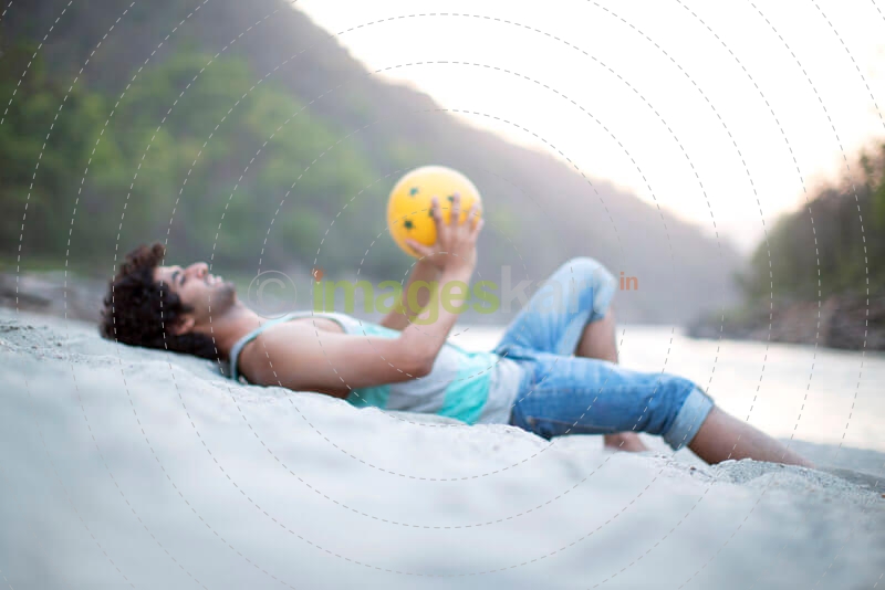 man lying on the sand playing with beach ball