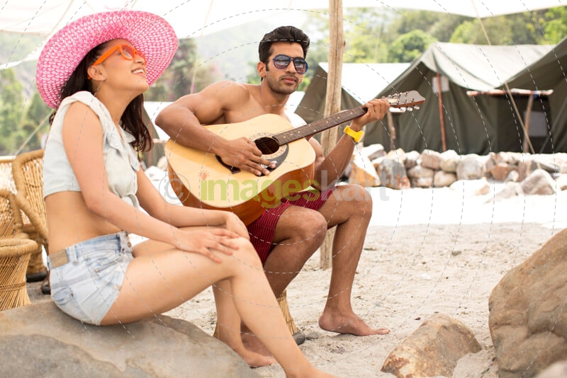 beach girl with a pink hat and funky glasses listening to the guitar