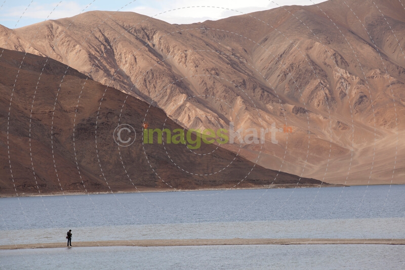 beautiful scenic view of desert mountains and a man standing on river 