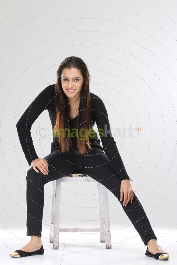 portrait of a stylish girl sitting on a stool against white background