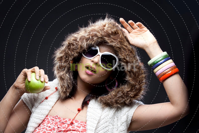 model in winter hoody holding a green apple