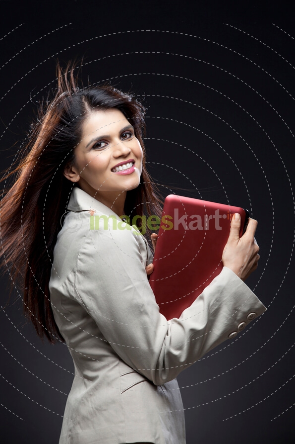 side pose of a corporate lady holding a pink laptop