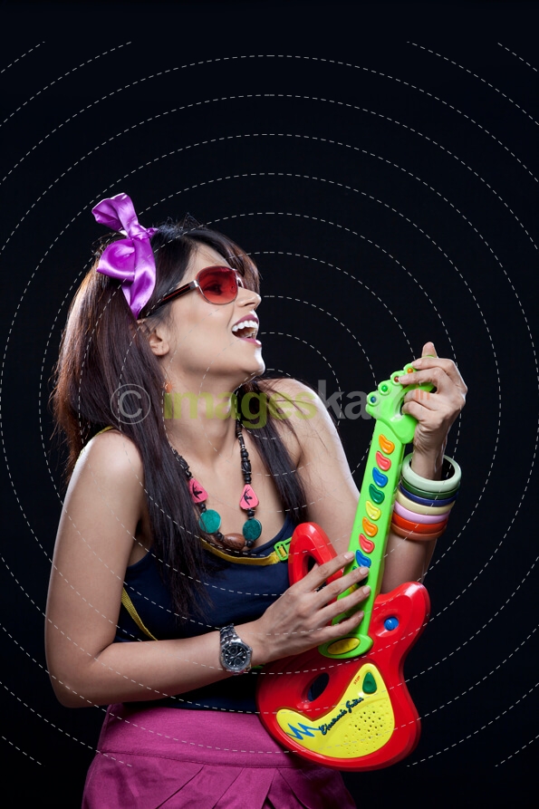 teenage girl with a side pose holding a toy guitar