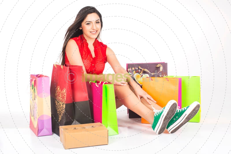 girl sitting and smiling with plenty of shopping bags