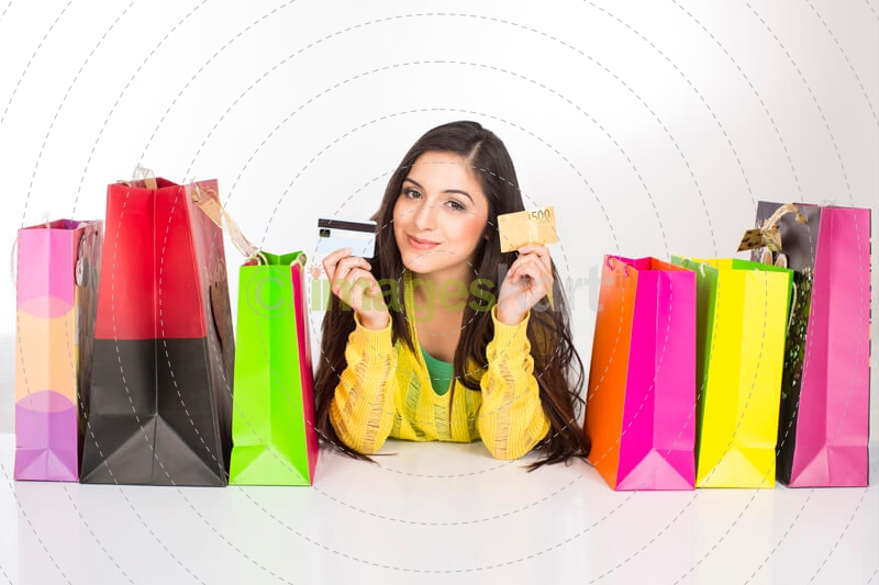 girl lying on the floor with shopping bags holding credit cards