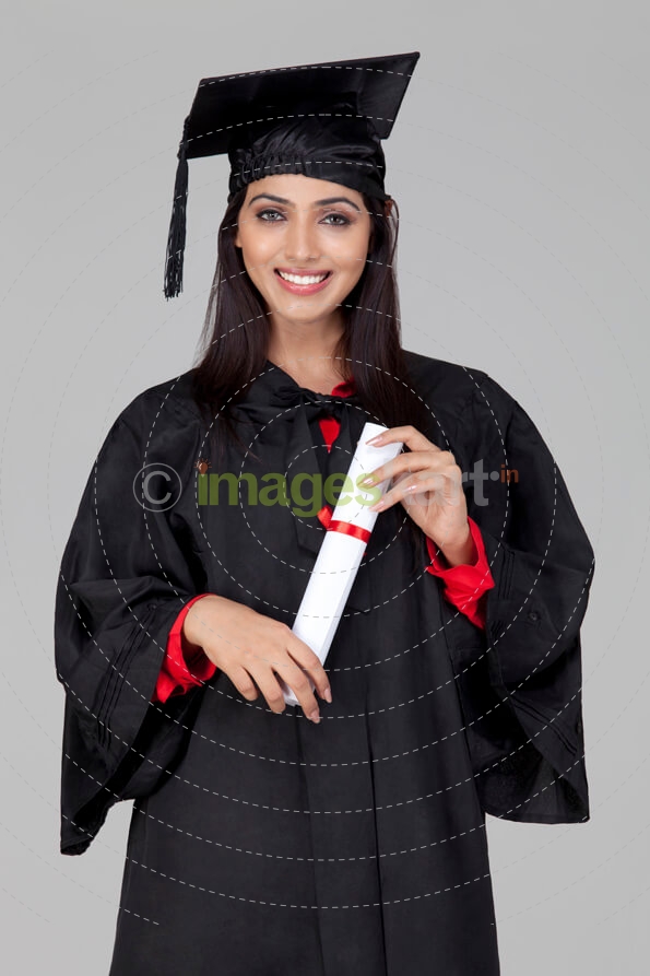 girl posing in graduation gown with degree in hand
