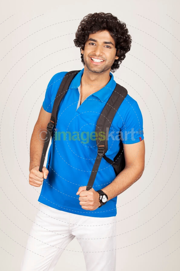 college boy posing while holding bag straps 