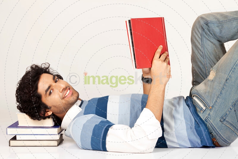 college boy lying down on pile of books 