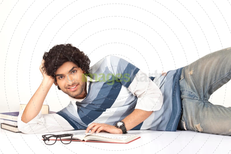 college boy lying around books posing with smile on his face 