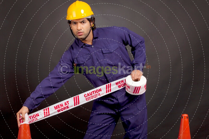 worker applying caution tape while looking at the camera 