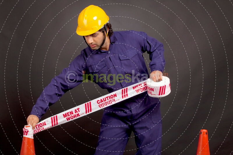 worker blocking the way with caution tape 